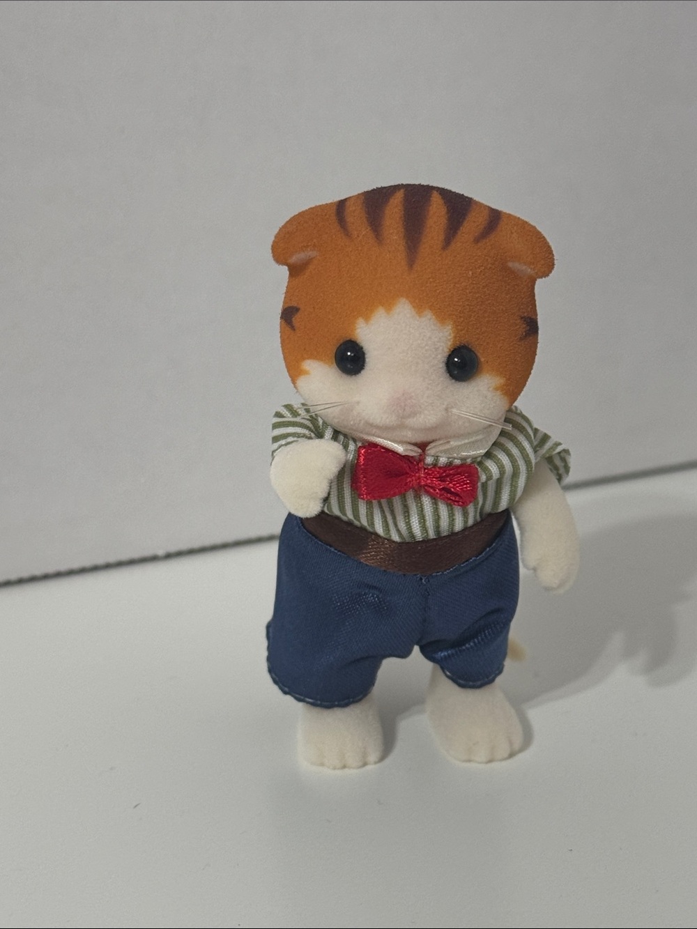 Calico critters Maple Cat figure wearing a striped shirt and blue pants